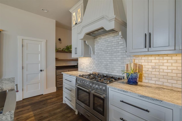 kitchen featuring backsplash, dark wood-type flooring, range with two ovens, custom exhaust hood, and white cabinets