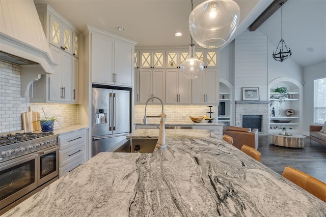 kitchen featuring premium range hood, open floor plan, stainless steel appliances, white cabinets, and light stone countertops