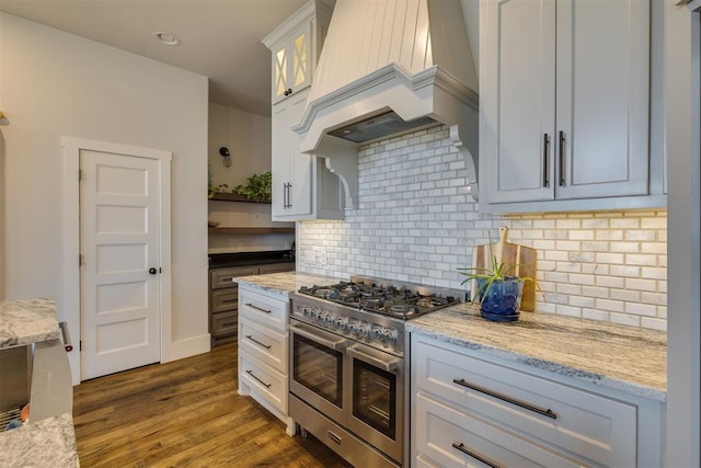 kitchen featuring double oven range, dark wood finished floors, white cabinetry, decorative backsplash, and custom exhaust hood