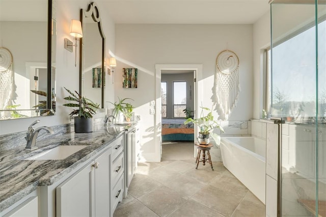 ensuite bathroom with a sink, a bathtub, ensuite bath, and double vanity