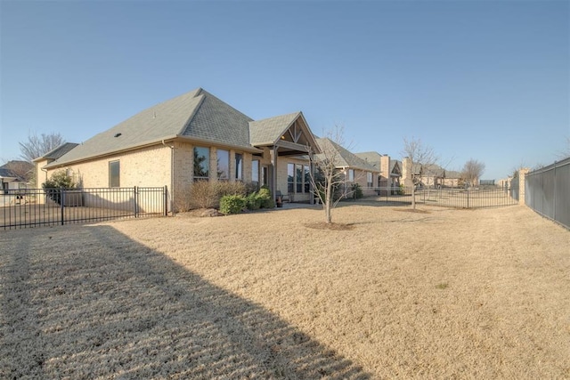 rear view of house with brick siding and a fenced backyard