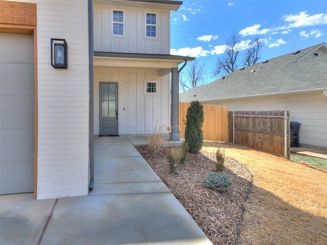 property entrance with board and batten siding and fence