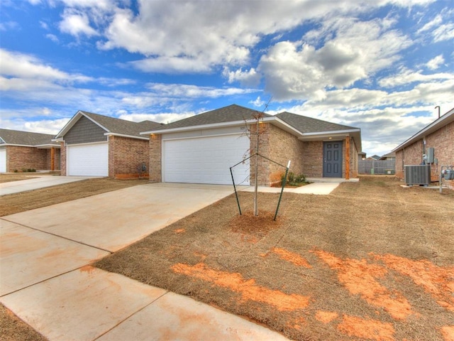 ranch-style home featuring a garage, concrete driveway, roof with shingles, central AC, and brick siding