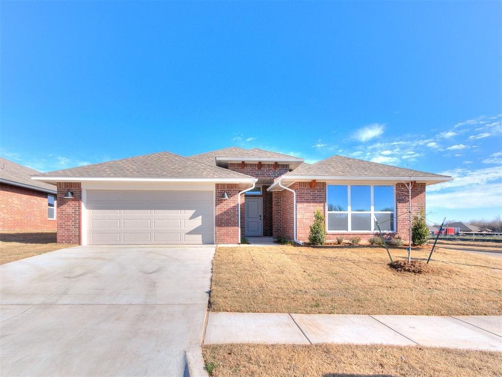 view of front of house featuring brick siding, a shingled roof, concrete driveway, an attached garage, and a front yard