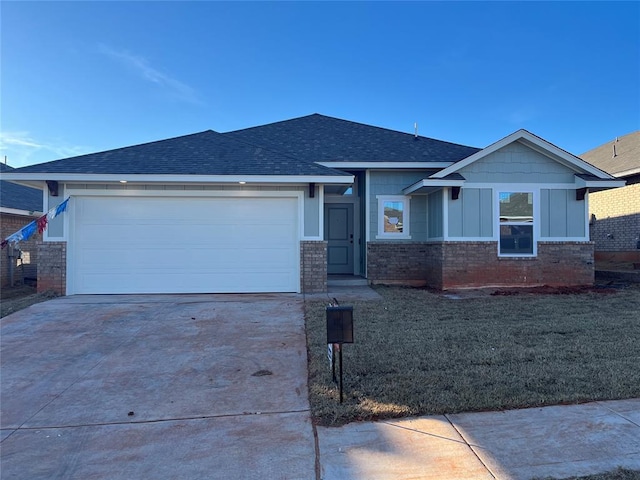 view of front of property with concrete driveway, roof with shingles, an attached garage, a front lawn, and board and batten siding