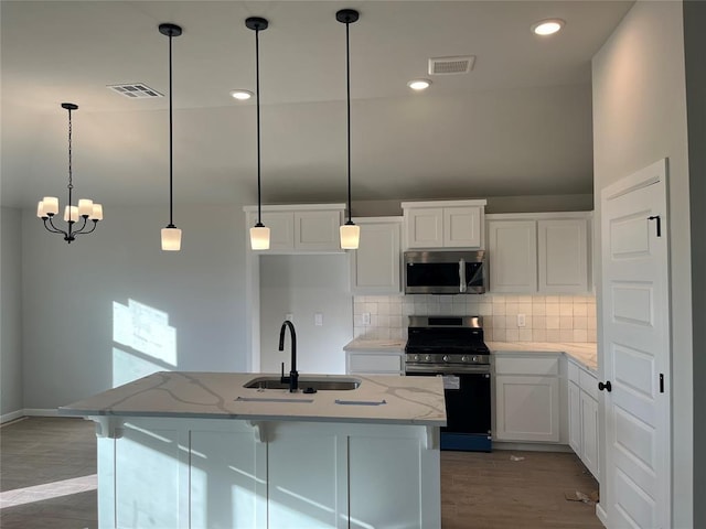 kitchen featuring appliances with stainless steel finishes, a sink, visible vents, and tasteful backsplash