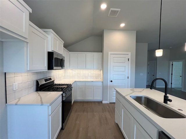 kitchen featuring visible vents, stainless steel microwave, wood finished floors, gas range oven, and a sink