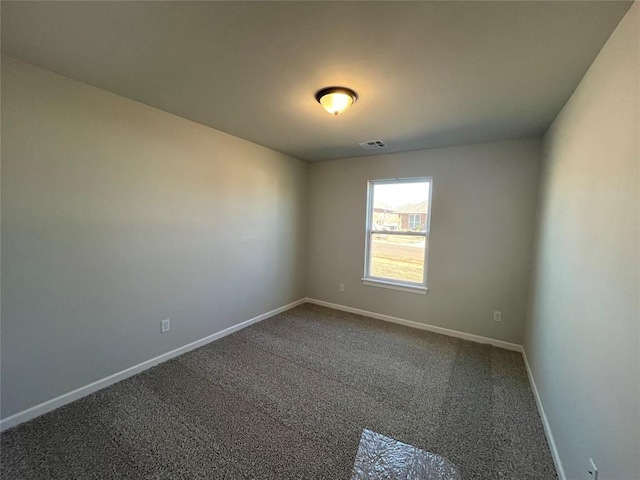 empty room with visible vents, dark carpet, and baseboards