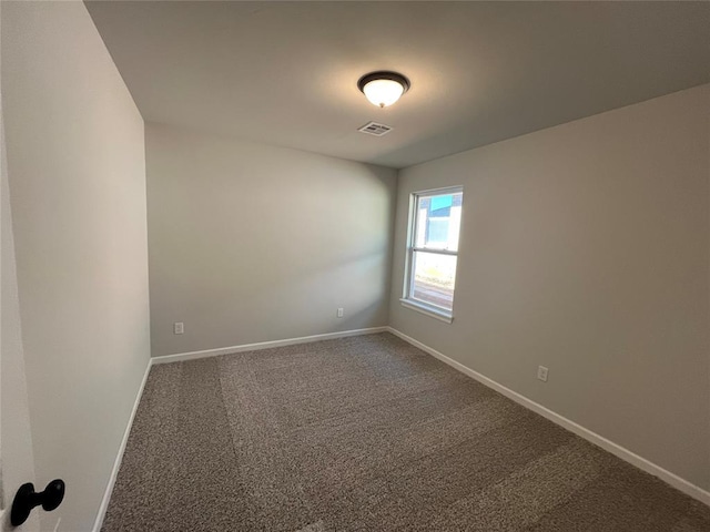 carpeted spare room featuring visible vents and baseboards