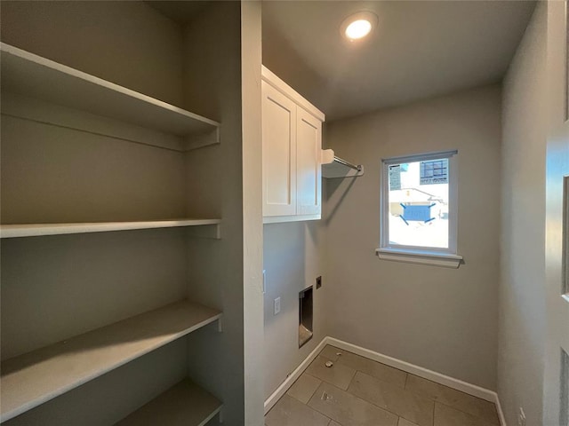 laundry area with electric dryer hookup, cabinet space, and baseboards