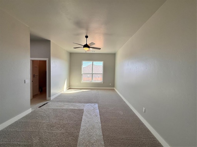 spare room with ceiling fan, light colored carpet, and baseboards