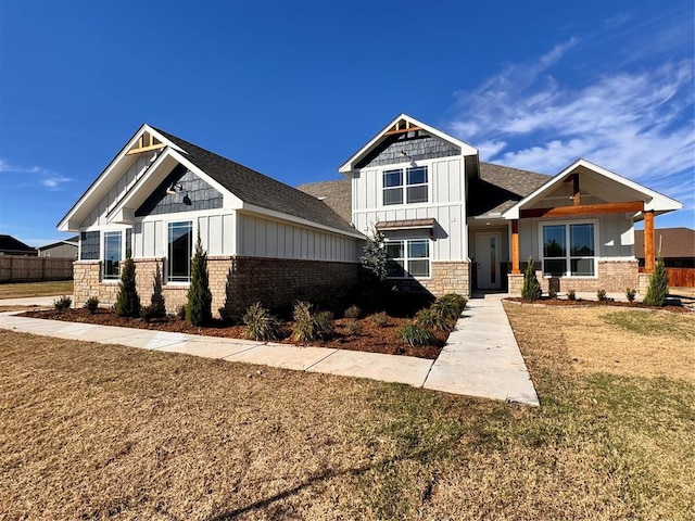 craftsman house with board and batten siding, a front yard, and fence