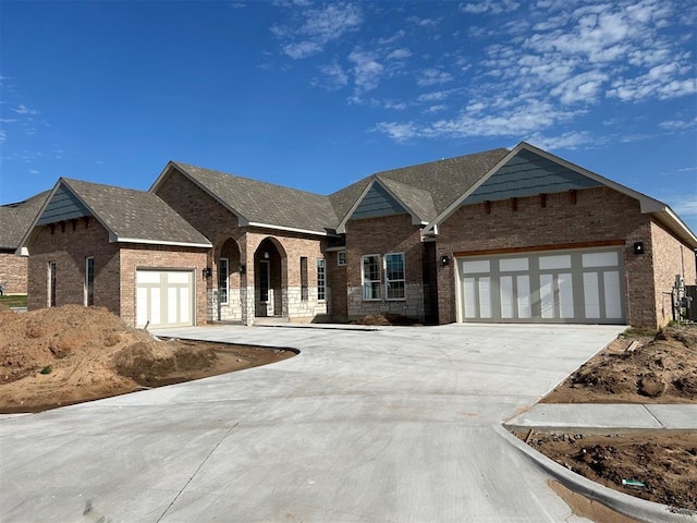 10109 NW 100th St, Yukon, OK 73099 - view of front facade featuring driveway, a garage, and brick siding