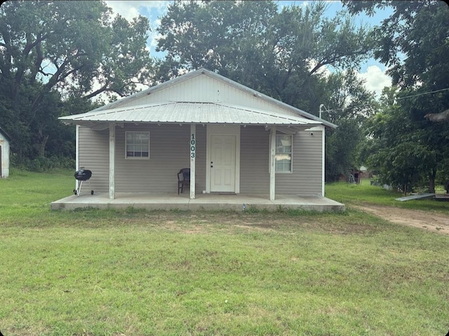 view of front of house with a porch, metal roof, and a front lawn