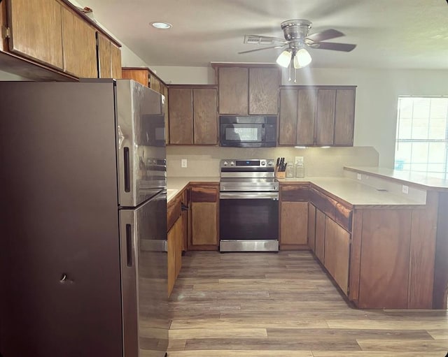 kitchen featuring a ceiling fan, light wood-style flooring, a peninsula, stainless steel appliances, and light countertops