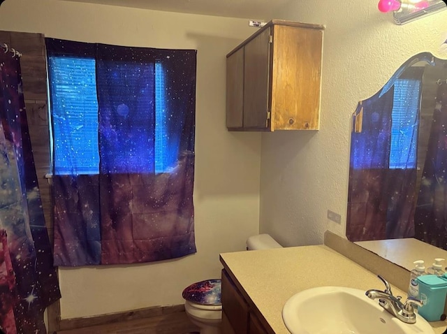 bathroom featuring a textured wall, vanity, and toilet