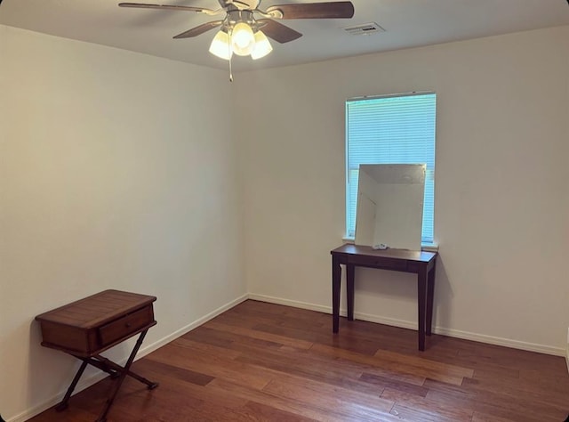 empty room featuring baseboards, visible vents, dark wood finished floors, and a ceiling fan