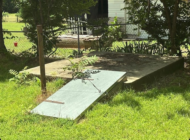 entry to storm shelter with fence and a lawn