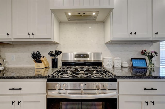 kitchen with stainless steel gas range, dark stone counters, white cabinets, and wall chimney range hood