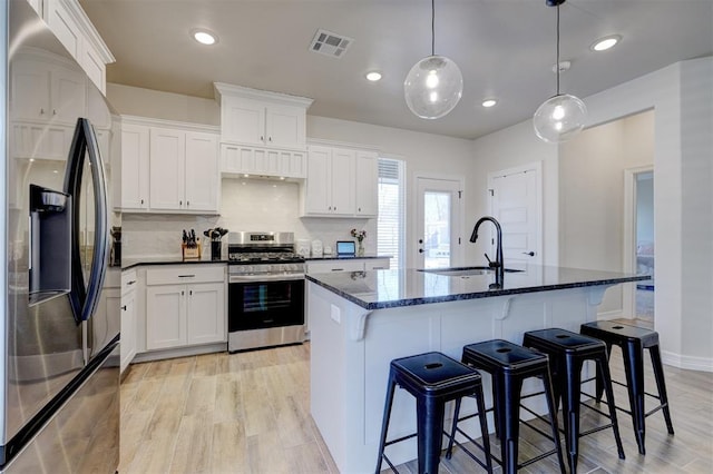 kitchen featuring stainless steel appliances, white cabinets, visible vents, and a sink