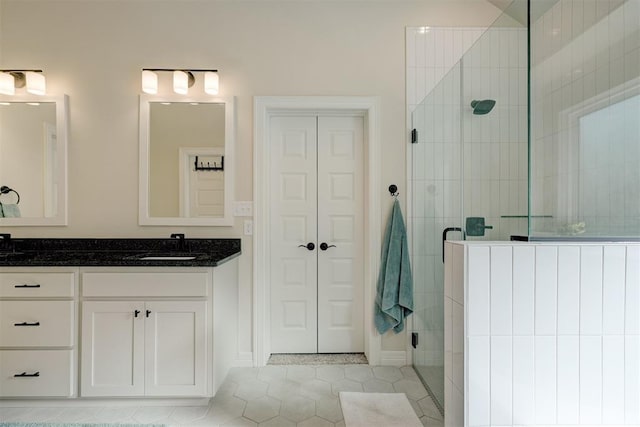 bathroom with a closet, tile patterned flooring, a shower stall, and vanity