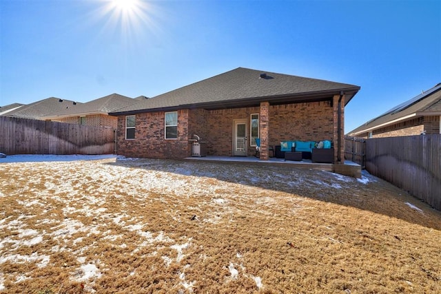 back of house with brick siding, roof with shingles, outdoor lounge area, a patio area, and a fenced backyard