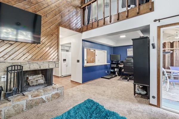 living area with a high ceiling, a fireplace, and carpet flooring