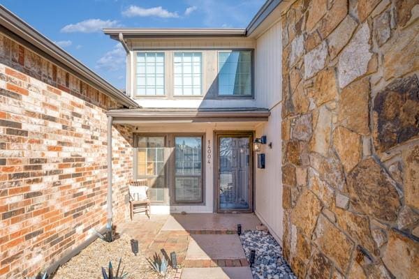 property entrance with a patio area and brick siding