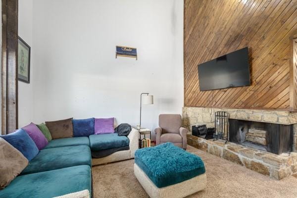 carpeted living room featuring a towering ceiling and a stone fireplace