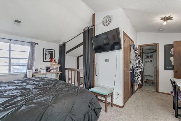 carpeted bedroom featuring lofted ceiling, visible vents, and baseboards