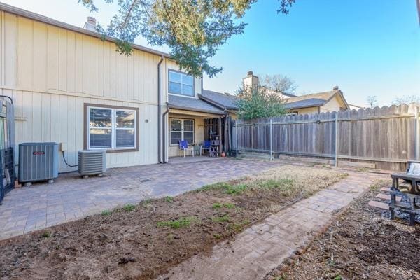 rear view of property featuring central AC unit, a patio area, and a fenced backyard