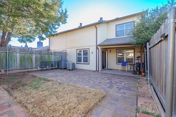 rear view of house with a patio area, a fenced backyard, and central AC