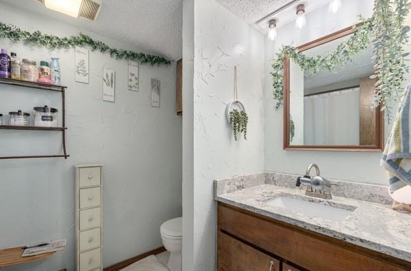 full bath featuring toilet, a textured ceiling, and vanity