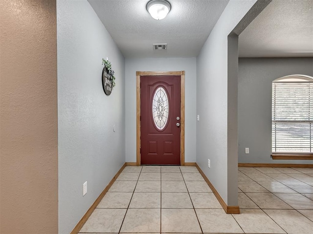 entryway featuring light tile patterned floors, a textured ceiling, and visible vents