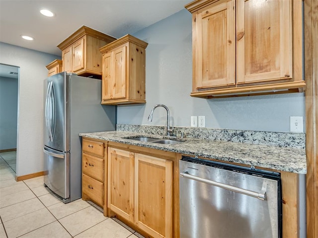 kitchen featuring light tile patterned floors, light stone counters, light brown cabinets, a sink, and appliances with stainless steel finishes