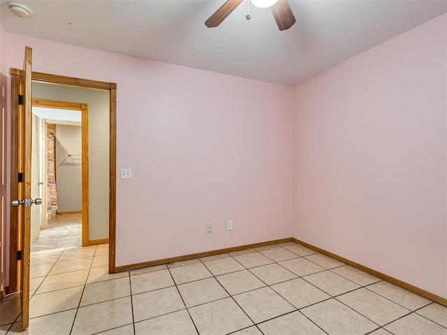 spare room featuring light tile patterned flooring, a ceiling fan, and baseboards