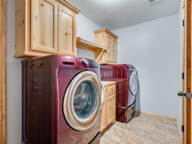 laundry room with washing machine and clothes dryer, visible vents, cabinet space, a textured ceiling, and baseboards