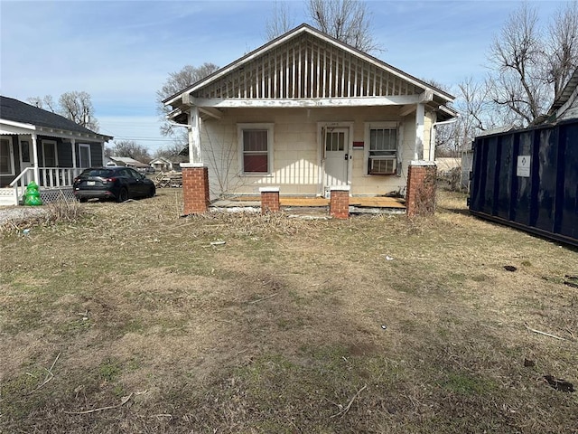 view of front of property with covered porch, a front yard, concrete block siding, and cooling unit