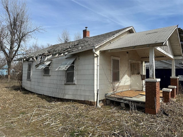 rear view of property with roof with shingles, a chimney, and cooling unit