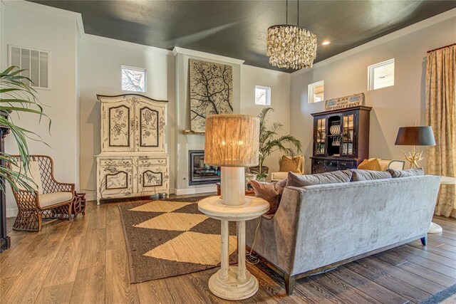 1212 W Wilshire Blvd, Nichols Hills, OK 73116 - living room featuring a glass covered fireplace, hardwood / wood-style flooring, a chandelier, crown molding, and recessed lighting