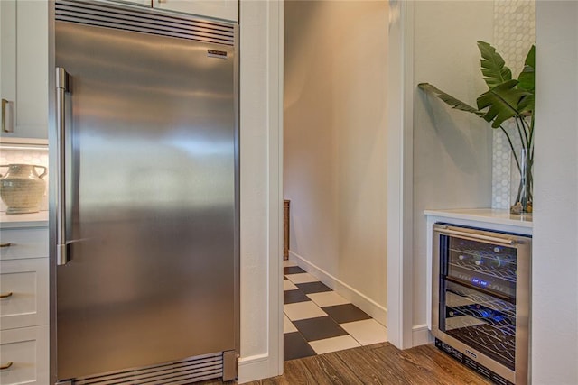 1212 W Wilshire Blvd, Nichols Hills, OK 73116 - detailed view of stainless steel built in fridge, wine cooler, light countertops, dark flooring, and baseboards
