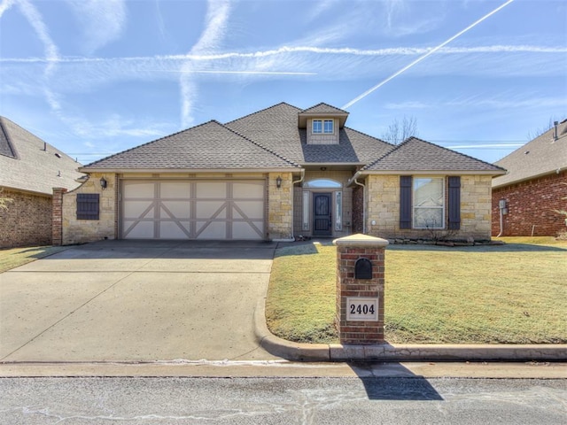 view of front of home with an attached garage, a shingled roof, stone siding, driveway, and a front lawn