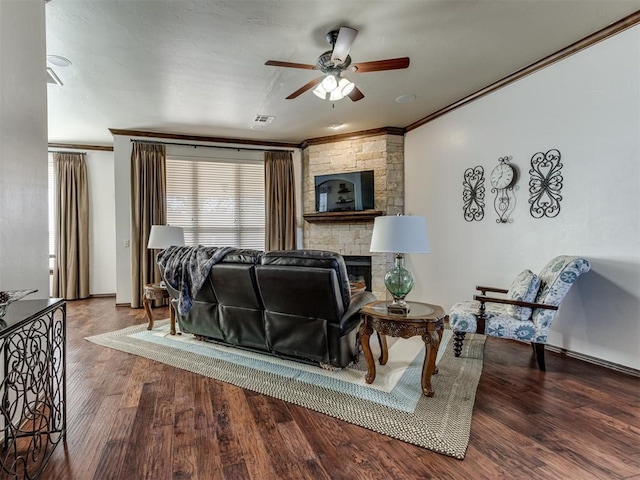 living room with visible vents, ornamental molding, wood finished floors, and a stone fireplace