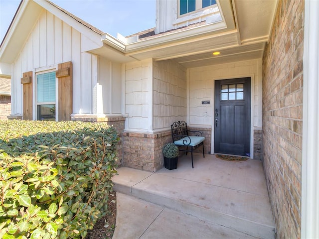 view of exterior entry with brick siding and board and batten siding