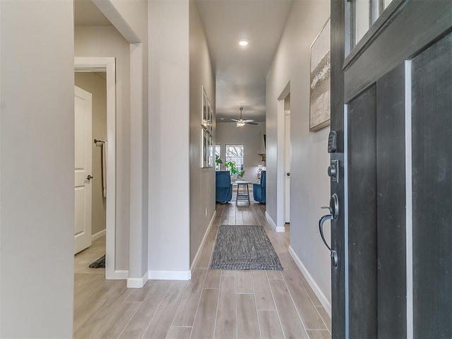 hallway featuring baseboards and wood tiled floor