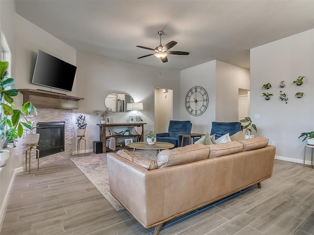 living room with ceiling fan, wood finish floors, a fireplace, and baseboards