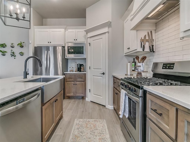 kitchen featuring white cabinets, custom range hood, hanging light fixtures, wood tiled floor, and stainless steel appliances