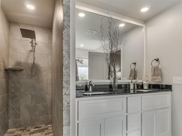 bathroom featuring a walk in shower, double vanity, a sink, and recessed lighting