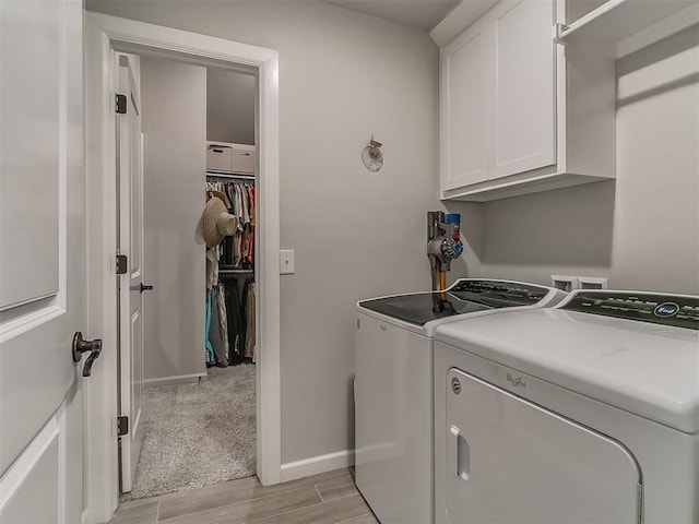 clothes washing area with washer and dryer, cabinet space, baseboards, and wood finish floors