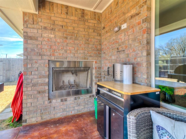 view of patio featuring an outdoor brick fireplace and fence